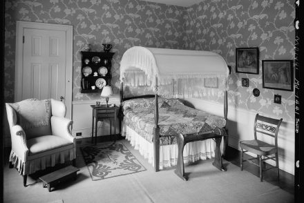 Antique filled bedroom with hand blocked wallpaper.